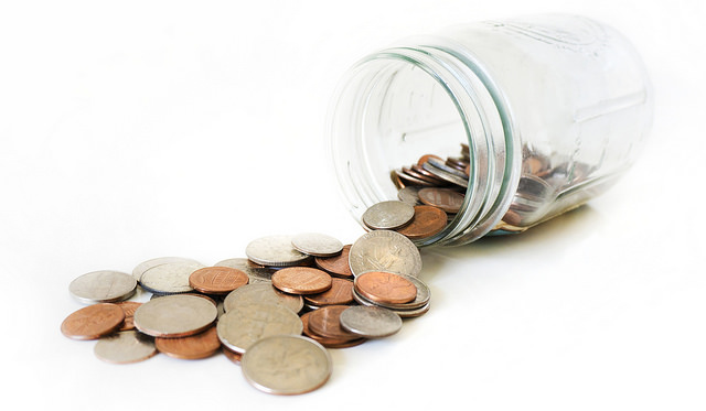 Coins coming out of a jar representing wasting money.