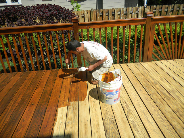 A painter staining a deck to get the house ready to sell.